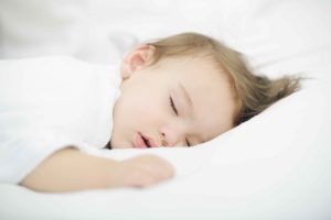 Baby sleeping on white bed with copy space